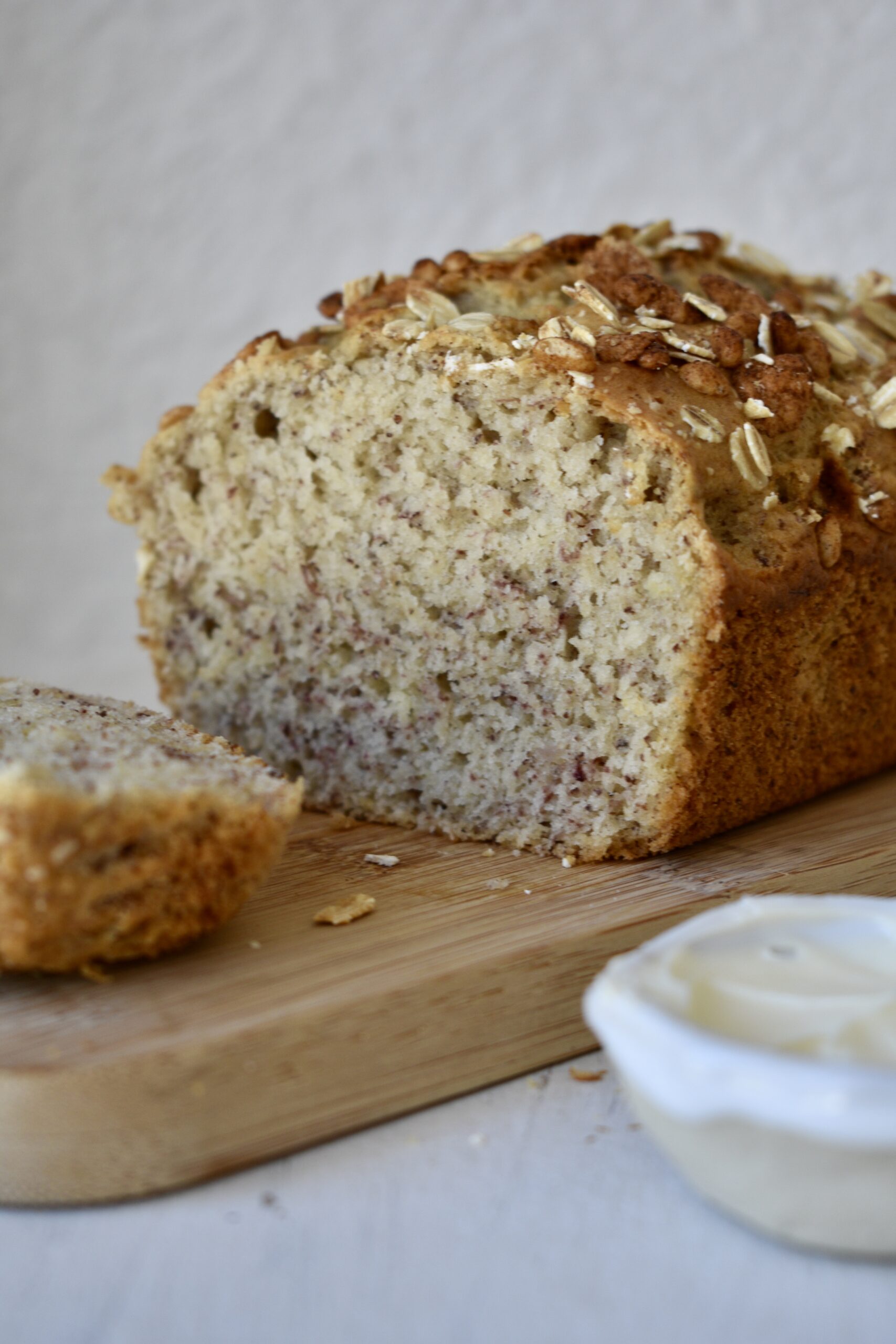 Banana Bread sliced on wooden board with ramekin of butter