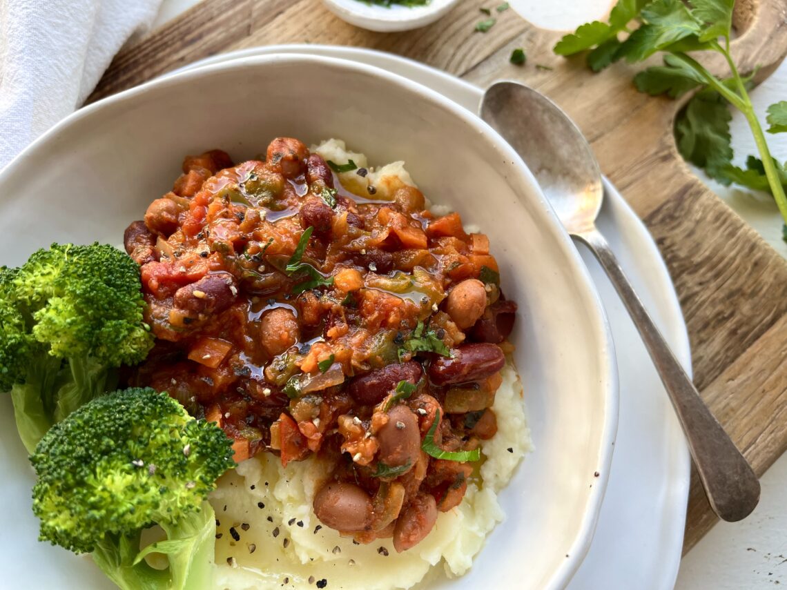 Ultimate Slow-Simmered Beans in Rich Tomato Sauce on a bed of mash potato with broccoli on the side