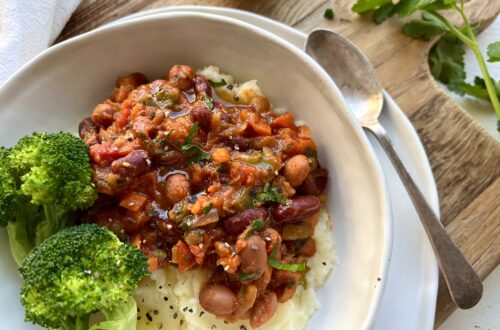 Ultimate Slow-Simmered Beans in Rich Tomato Sauce on a bed of mash potato with broccoli on the side